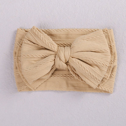 Side view of a baby's head with a blue soft elastic bow headband, cozy fit