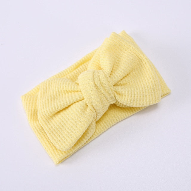Soft pink baby elastic bow headband on a white background, product shot