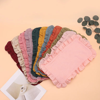 Soft pink muslin cotton gauze burp cloth with delicate ruffle edge, perfect for newborn feeding and infant care.