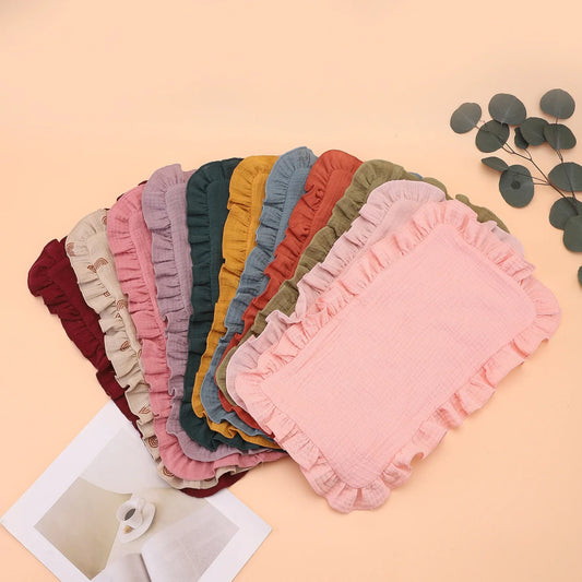Soft pink muslin cotton gauze burp cloth with delicate ruffle edge, perfect for newborn feeding and infant care.