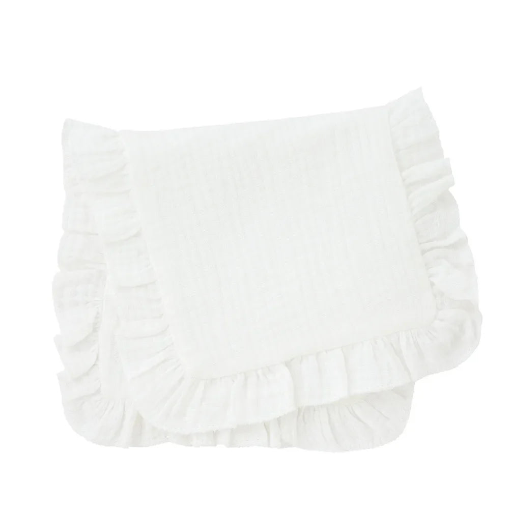 Hand holding a folded muslin burp cloth with ruffle edge, showcasing its soft texture for baby's skin.