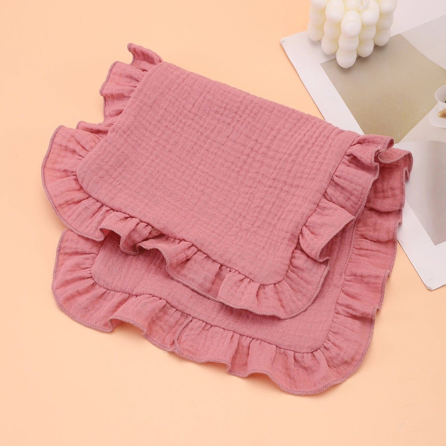 Natural cream colored muslin burp cloth with ruffle edge, offering gentle absorbency for baby care.