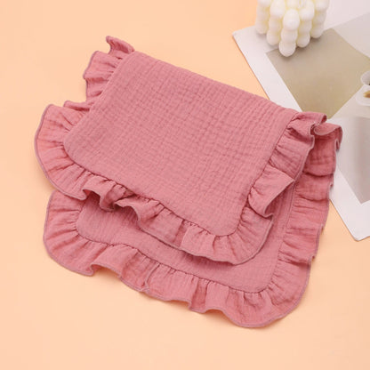Natural cream colored muslin burp cloth with ruffle edge, offering gentle absorbency for baby care.