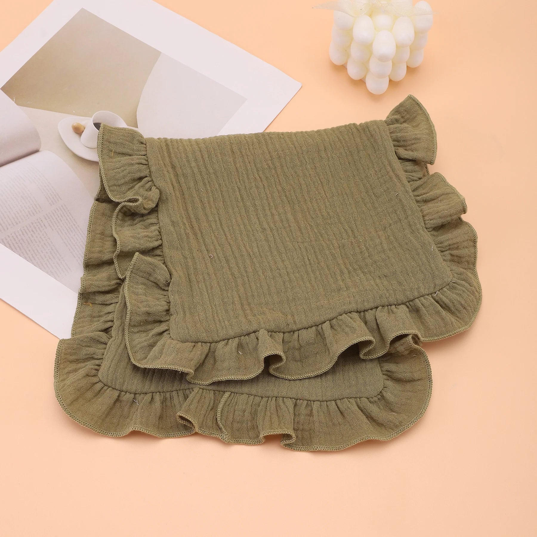 Detailed view of the textured cotton gauze fabric on a ruffled baby burp cloth, highly absorbent.