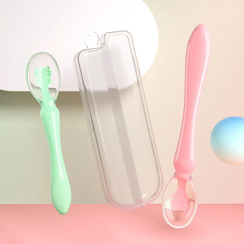 Toddler holding a blue silicone feeding spoon, practicing self-feeding skills