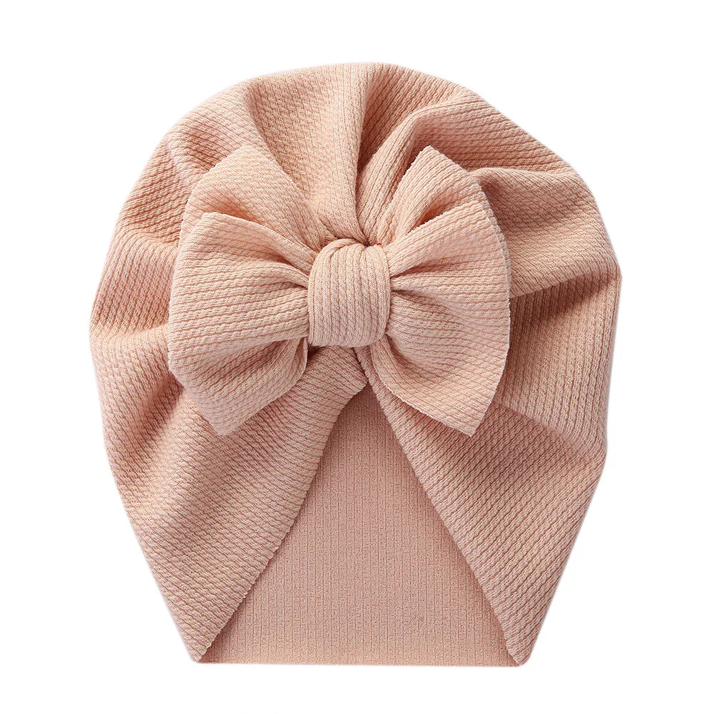 Back view of a baby topknot turban showing elasticated polyester material for snug fit