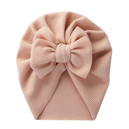 Back view of a baby topknot turban showing elasticated polyester material for snug fit
