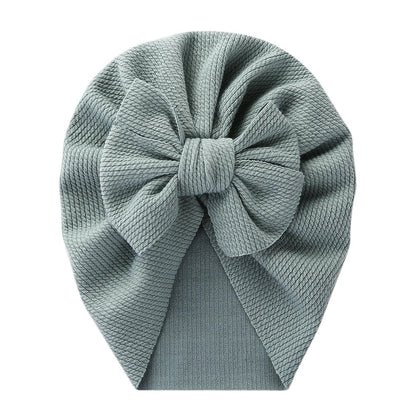 Baby model wearing a vibrant red topknot turban, stylish polyester infant headwrap