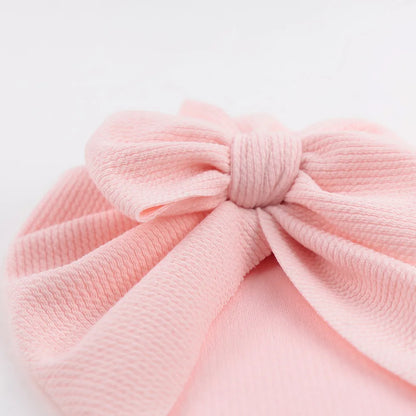 Close-up of a white topknot turban hat, showcasing soft polyester fabric for baby