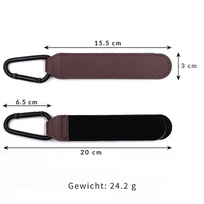 Two black vegan leather stroller hooks securely attached to a pram handle, holding a diaper bag.