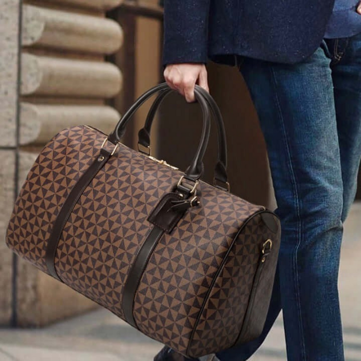 Model carrying a sleek black unisex duffle bag, showcasing its comfortable design for travel & gym. Stylish everyday carry.
