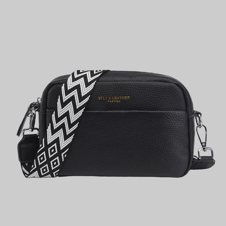 Stylish women's black crossbody bag featuring a unique geometric shoulder strap. Versatile everyday fashion accessory.