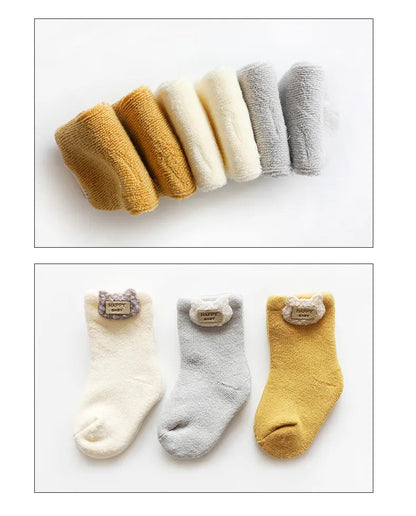 Three pairs of cute animal baby socks in white, red, and blue, showcasing delightful designs.