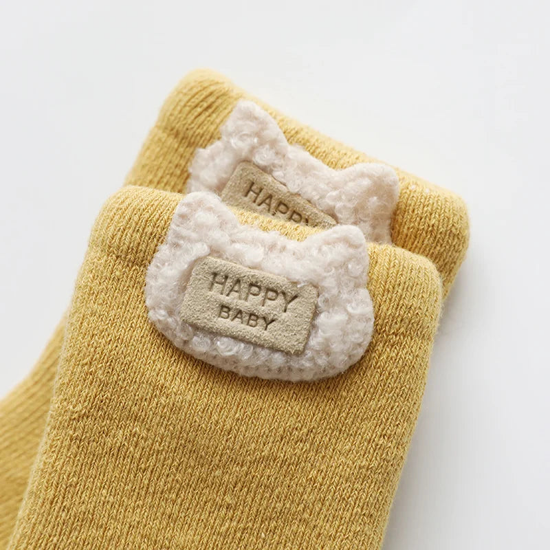 Bundle of three unisex baby socks with cute animal motifs, soft and warm for colder months.
