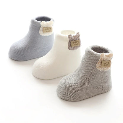 A cozy pair of white baby socks with a cute bear design, suitable for winter and infant comfort.