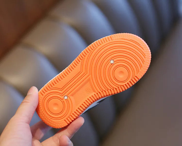 Young child putting on their own easy on/off anti-slip kids shoes, promoting independence