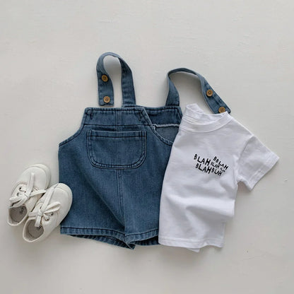 Full shot of two-piece toddler outfit: light blue denim t-shirt and darker blue denim jumpsuit.