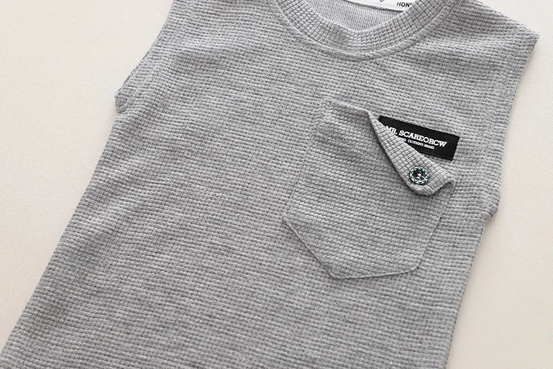 Toddler boy sitting comfortably in his blue and orange summer sports outfit, durable cotton play clothes.