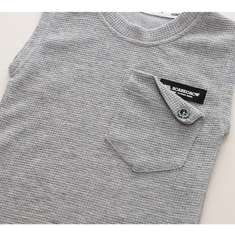 Detail of the neckline on a toddler boy's blue sleeveless cotton top, designed for comfort and ease of movement.