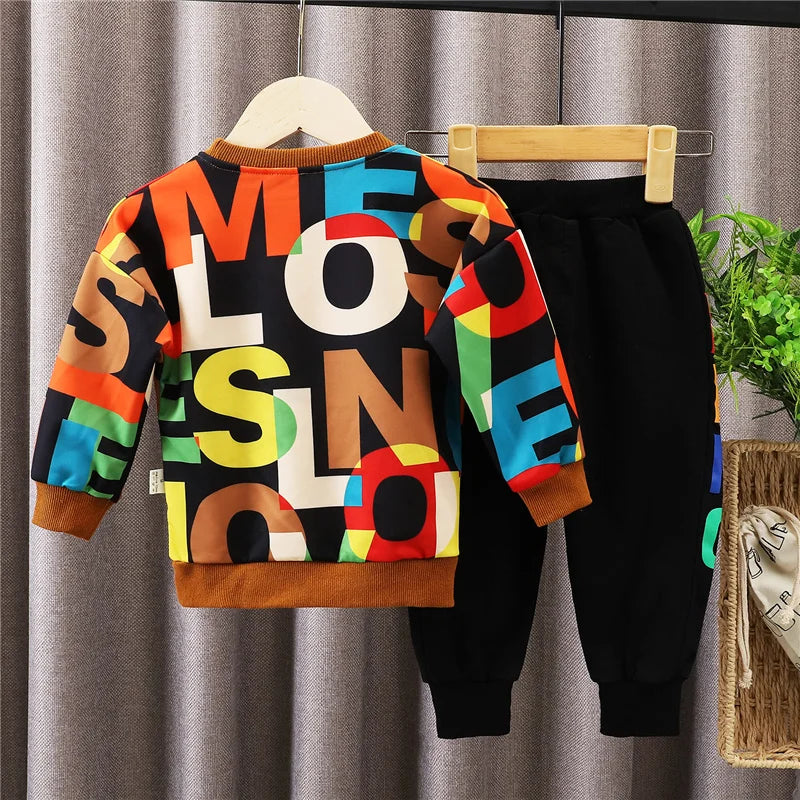 Baby boy clothes: blue long-sleeve cotton t-shirt and pants set, flat lay on a wooden surface.