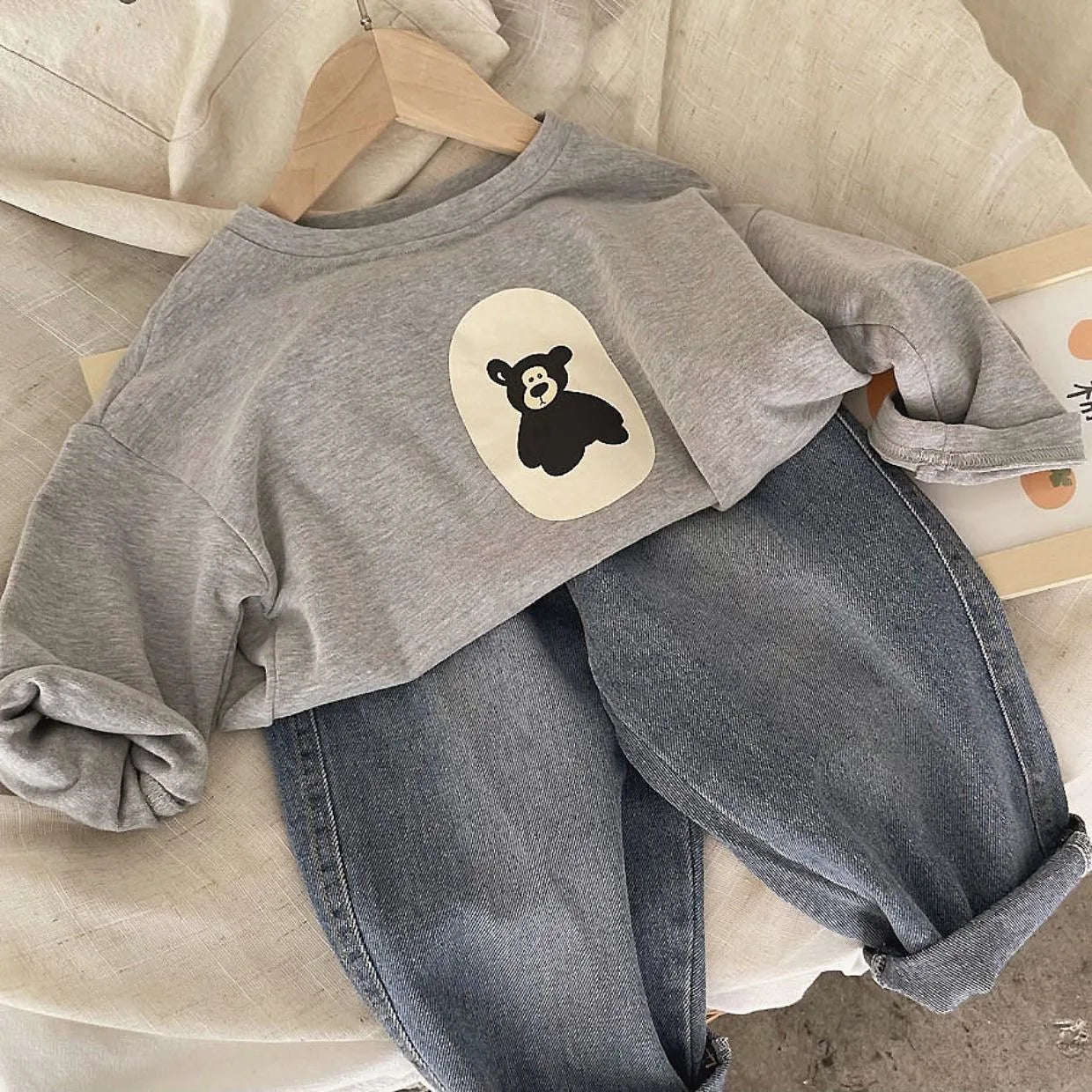 Close-up of a kids' bear print cotton sweatshirt, showing detailed animal graphic and fabric texture.