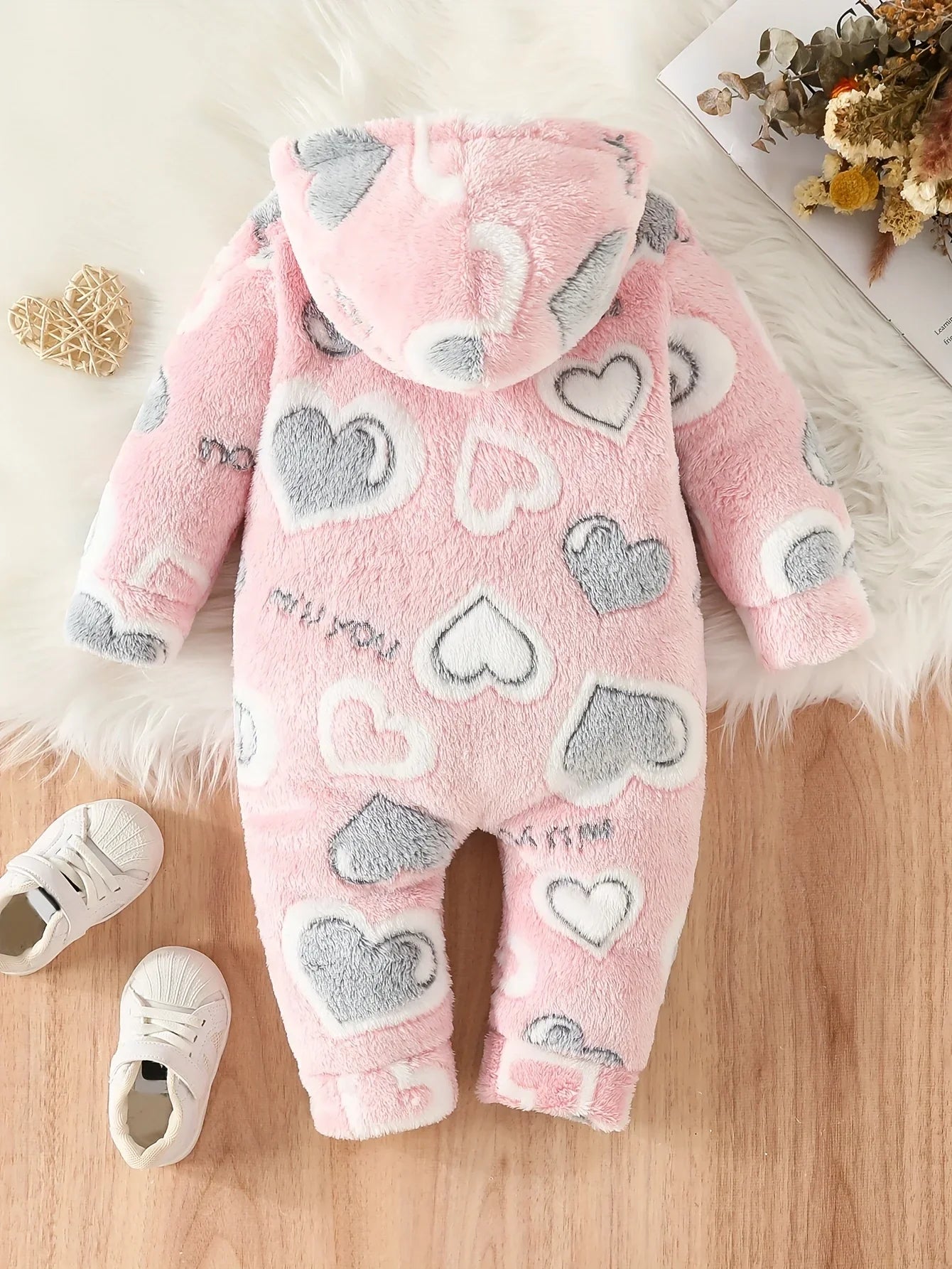 Close-up of fuzzy pink heart pattern on baby hooded winter romper, soft polyester