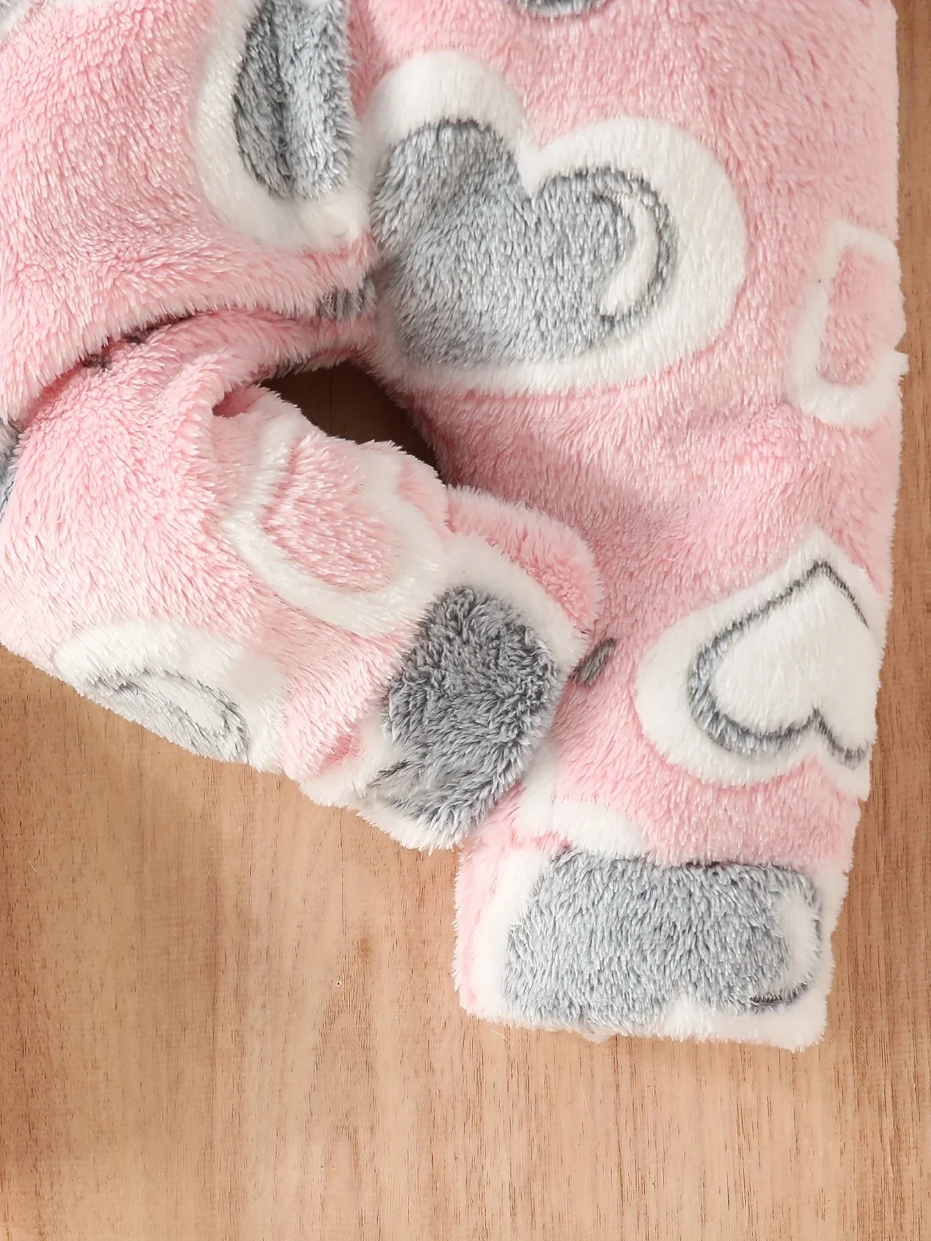 Detail of hood and fuzzy texture on pink heart baby winter romper, polyester fabric