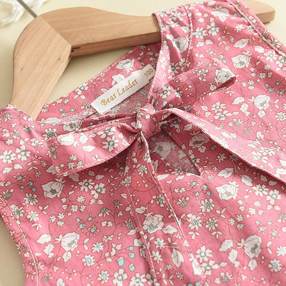 Cute toddler girl modeling a stylish floral print short-sleeve top and comfy pants outfit.