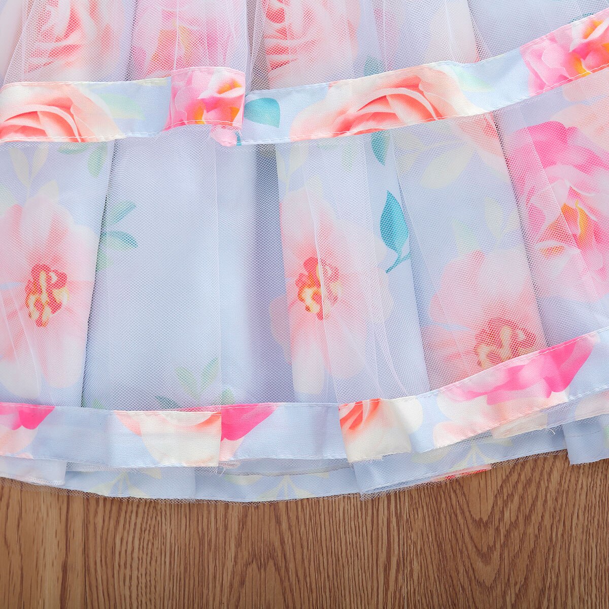 Detailed view of the lace and floral pattern on a girl's pleated princess dress, toddler size.