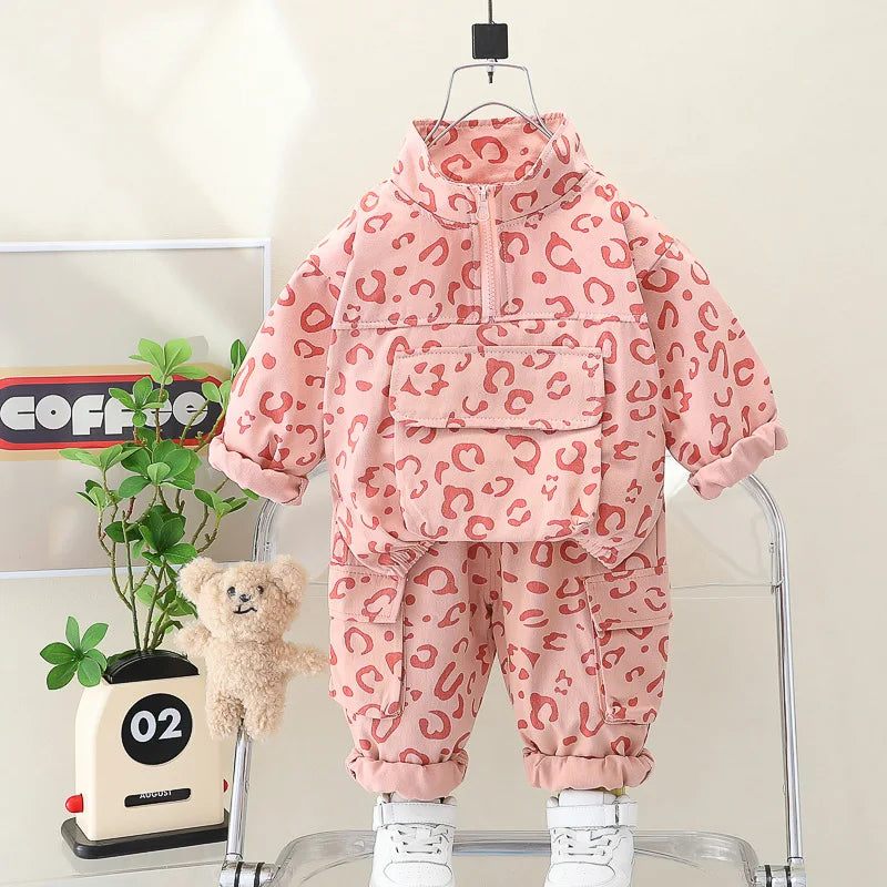 Happy toddler boy playing in a stylish leopard print sweatshirt and pants set, playful children's wear.