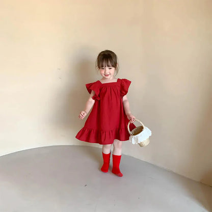 Young girl admiring herself in a mirror, wearing a vibrant red short sleeve A-line play dress.