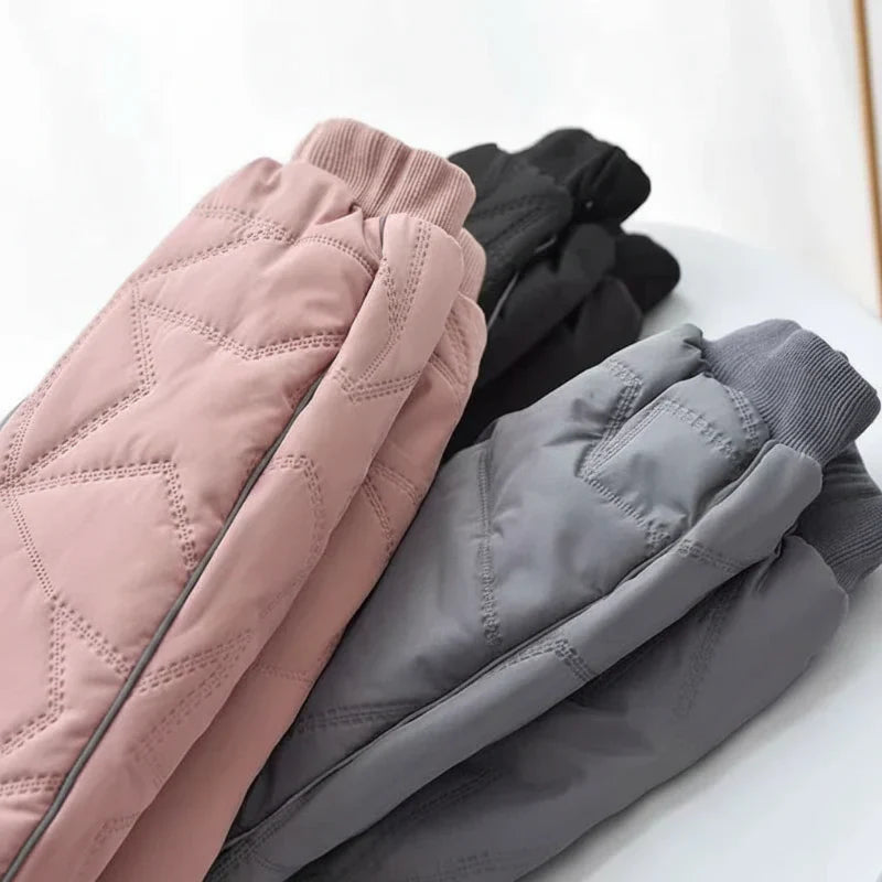 Toddler girl in pink waterproof fleece-lined snow pants, playing in winter snow.
