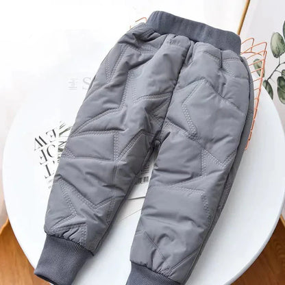 Little girl jumping in purple waterproof toddler snow pants with reinforced knees.