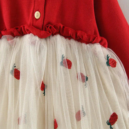 Infant girl smiling, wearing a beautiful red long sleeve lace tutu dress for special occasions.