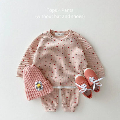 Toddler girl laughing while wearing a cute multi-print cotton clothes set, great for autumn playwear.