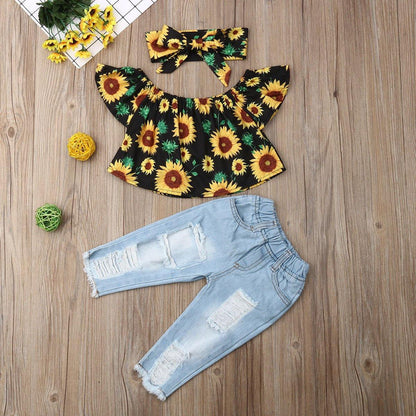 Toddler girl's off-shoulder sunflower print top with ripped jeans and matching headband, perfect for summer playwear.