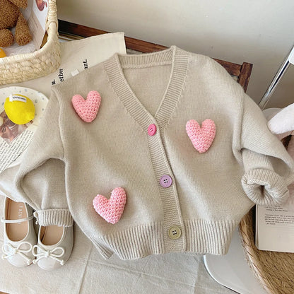 Girls' long sleeve knitwear sweater in light pink featuring a prominent white heart on the front