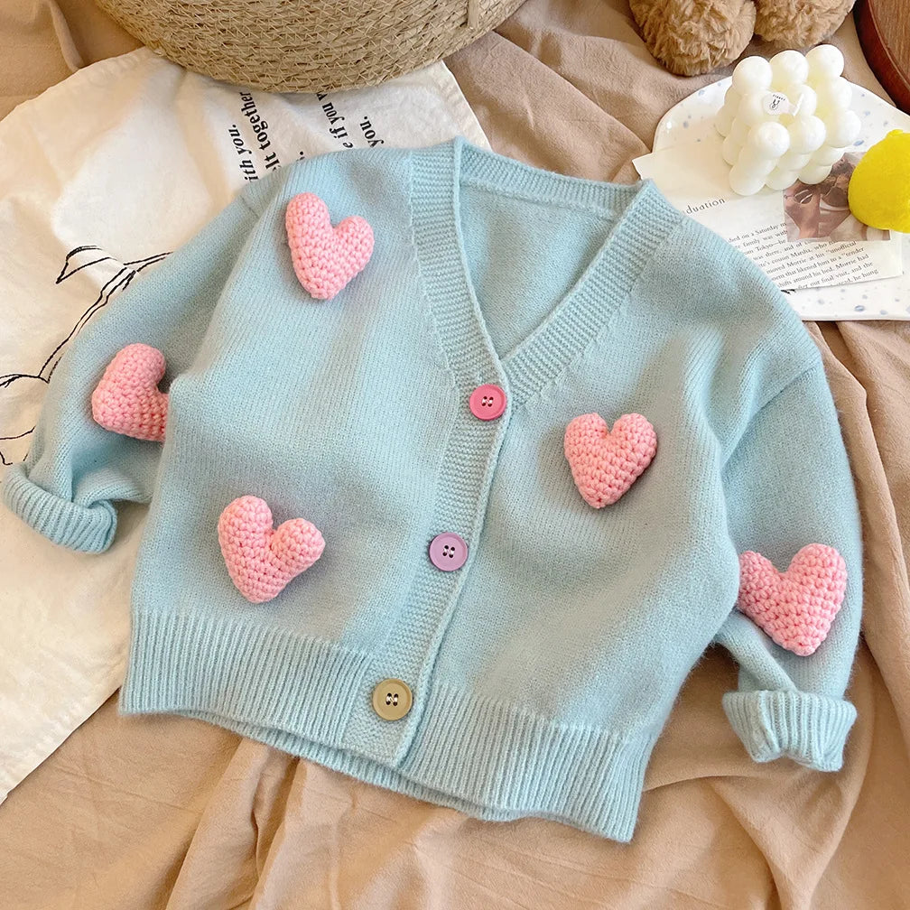 Baby girl wearing a comfortable knit sweater with a charming heart pattern, ideal for cold weather