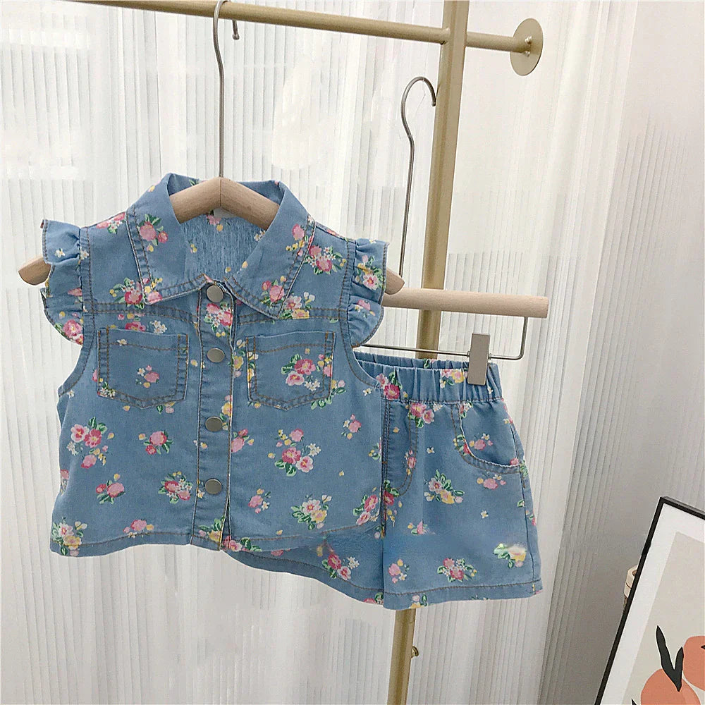 Full view of a girls' summer outfit featuring a vibrant floral top and practical denim shorts