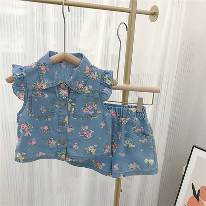 Full view of a girls' summer outfit featuring a vibrant floral top and practical denim shorts