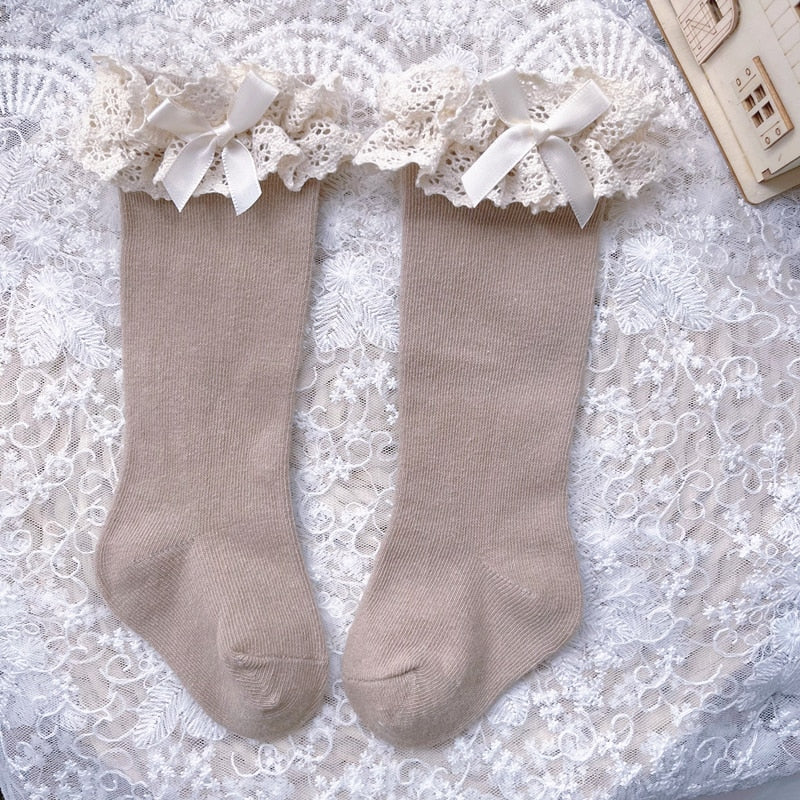 Kids' fashion: white knee-high ruffle bow socks, ideal for special occasions.