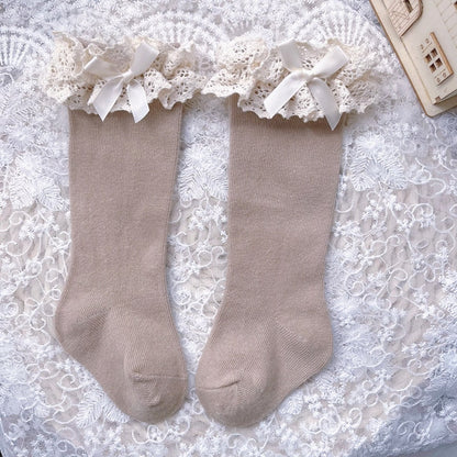 Kids' fashion: white knee-high ruffle bow socks, ideal for special occasions.