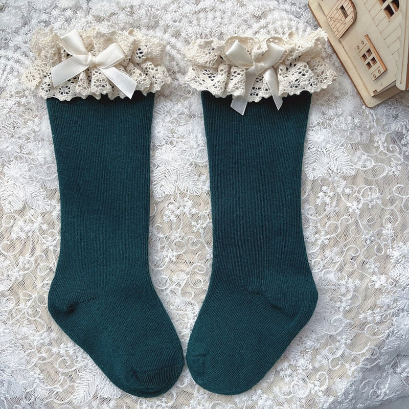 Non-slip knee-high socks for toddlers with elegant ruffle and bow detail.