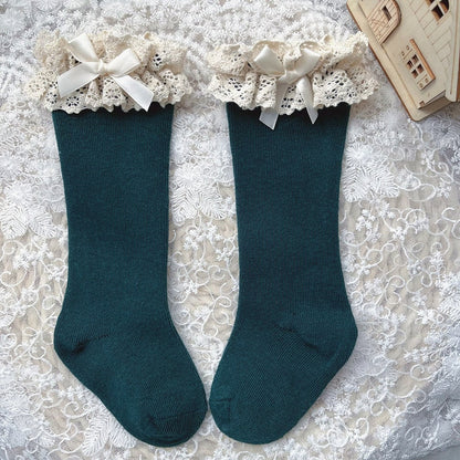 Non-slip knee-high socks for toddlers with elegant ruffle and bow detail.