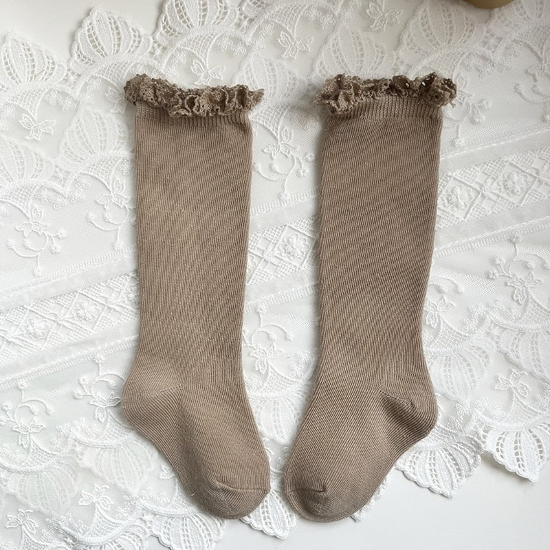 Fashionable knee-high socks for baby girls with classic ruffle and bow design.
