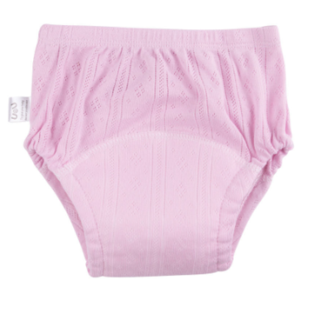 Happy baby boy wearing yellow cotton potty training pants, playing on floor, comfortable kids apparel.