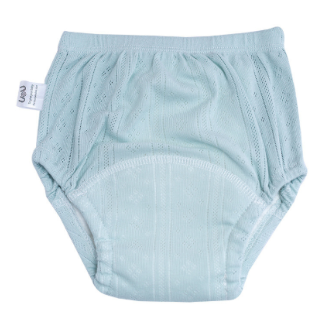Mother helping toddler put on green washable cotton training pants, promoting independence, baby clothing.