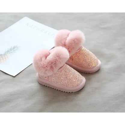 Happy child jumping in the snow, wearing practical and stylish glitter winter boots