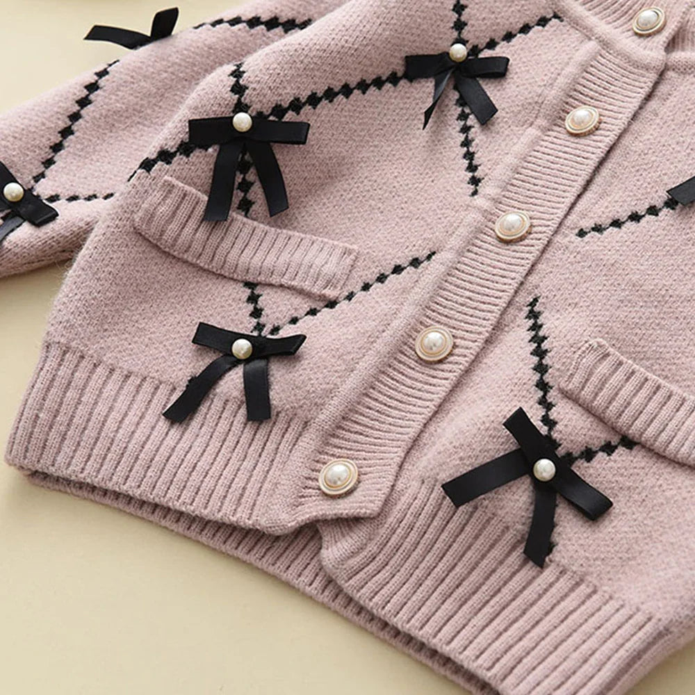 Happy little girl playing while wearing her pink knitted winter sweatshirt and pants set, durable.