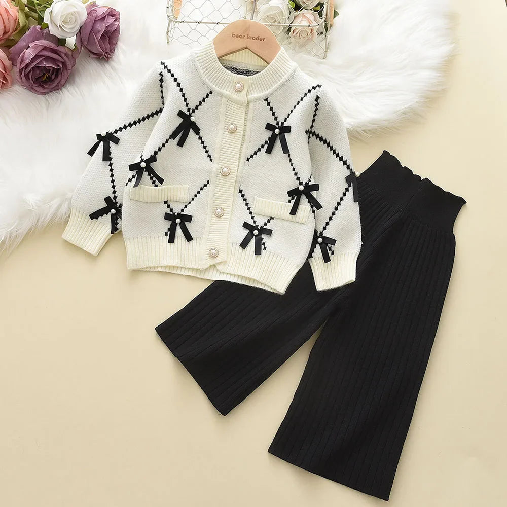 Side view of a toddler girl showcasing the fit of her knitted winter sweatshirt and pants set.